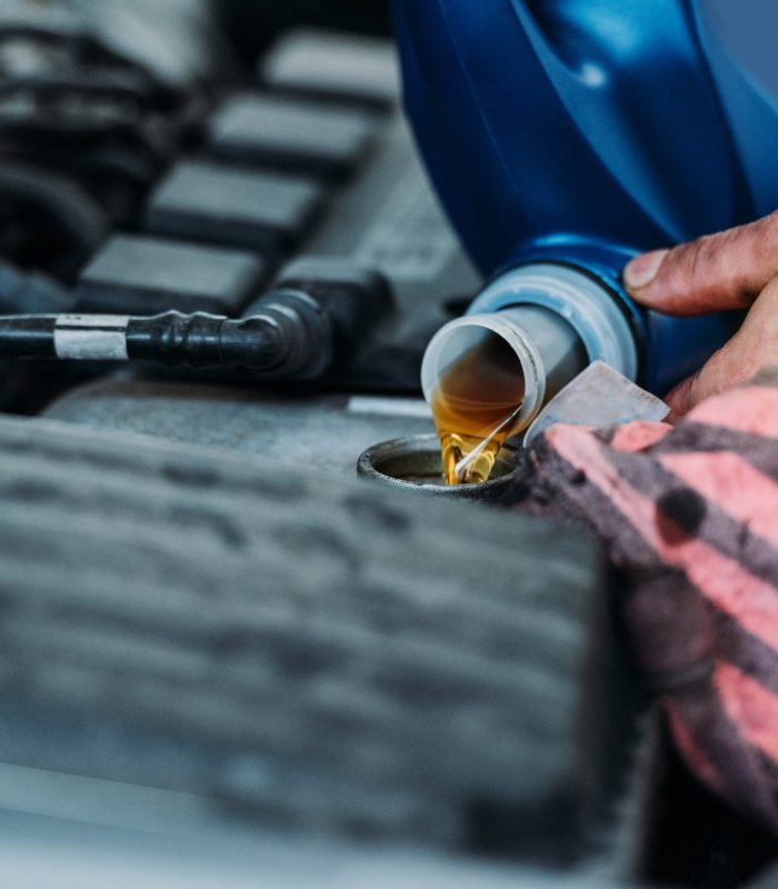 Cropped shot of automechanic changing motor oil in a repair shop.