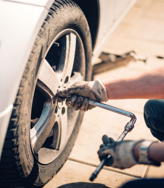 Tire maintenance, damaged car tyre or changing seasonal tires using wrench